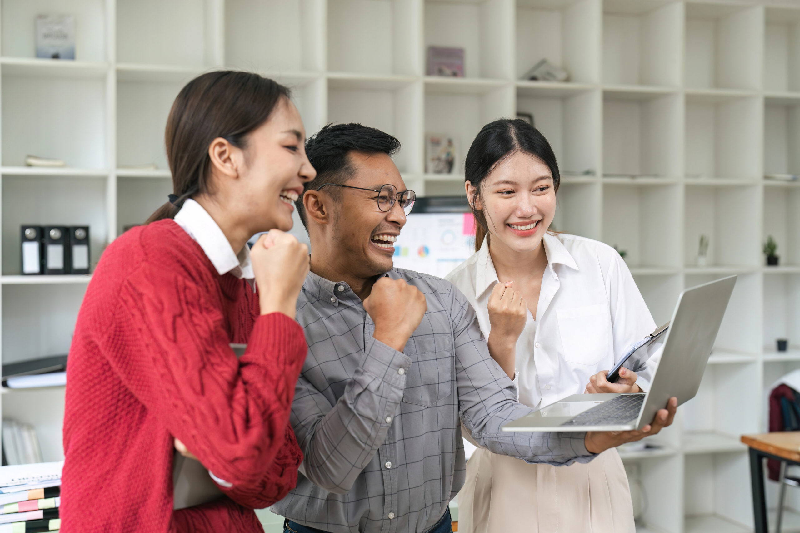 young asian businessman cheering in front of laptop | Solutionariez